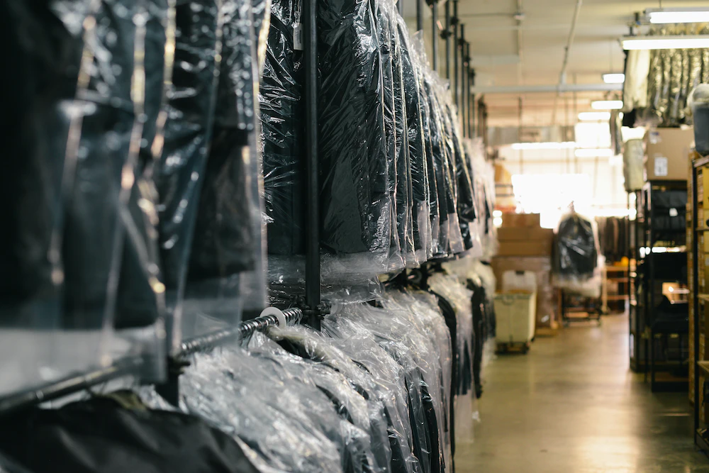 A warehouse with a lot of clothes hanging on racks specializing in wedding dress preservation