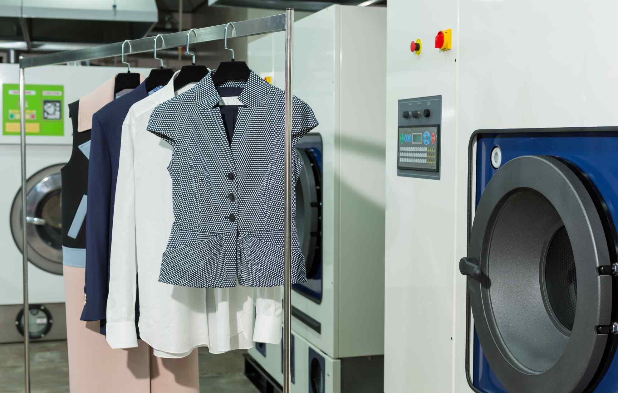 A laundry room with clothes hanging on racks, offering dry cleaning services.